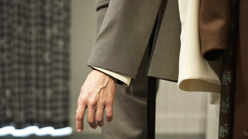 Zakupy z doradcą: dłoń wybierająca żakiet z wieszaka w butiku